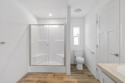A white bathroom with wood floors and a shower.